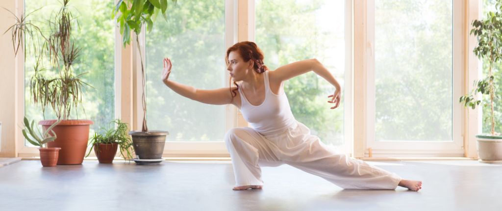 Rothaarige Frau bei der Ausübung der Qigong Formen.